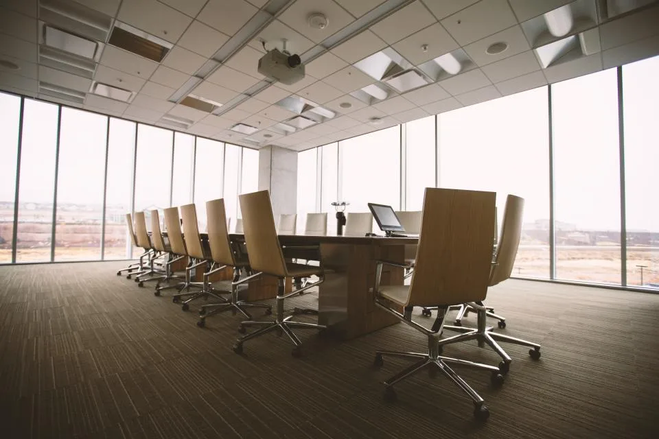 Empty modern conference room with a long table, office chairs and large windows