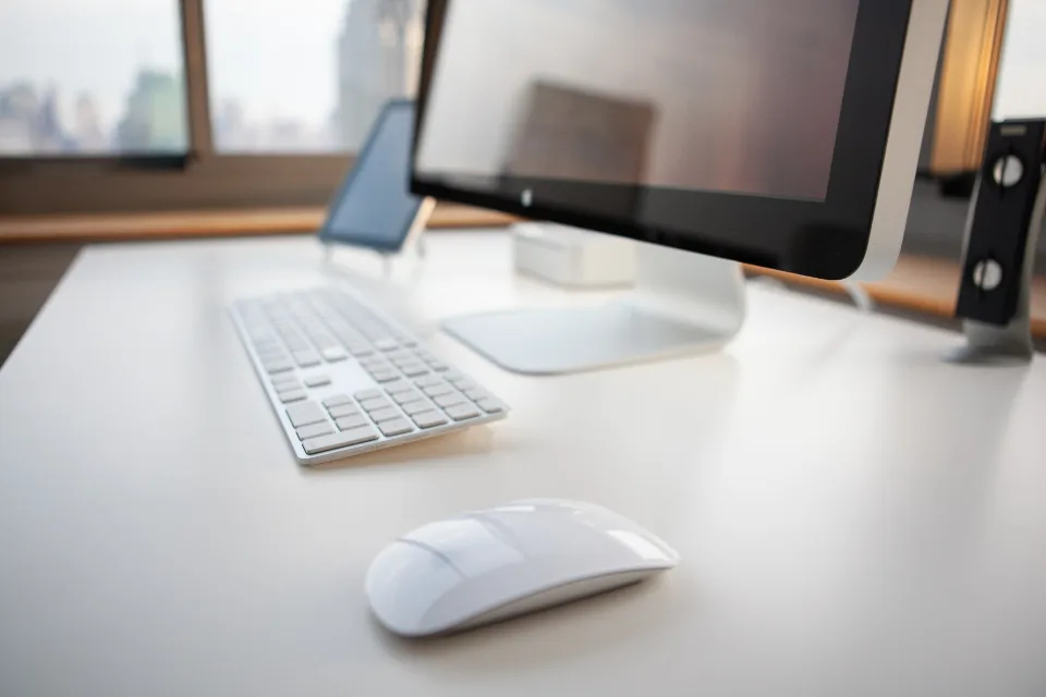 Clean white desk with a monitor, keyboard and mouse in a bright home office