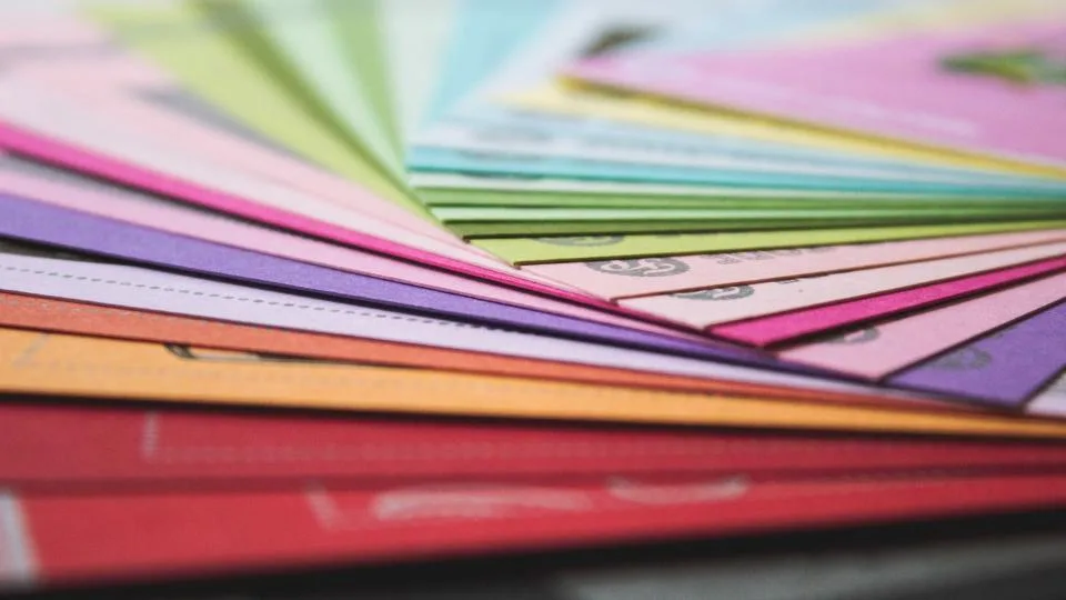 Fanned stack of colored paper samples in pink, green, purple and red