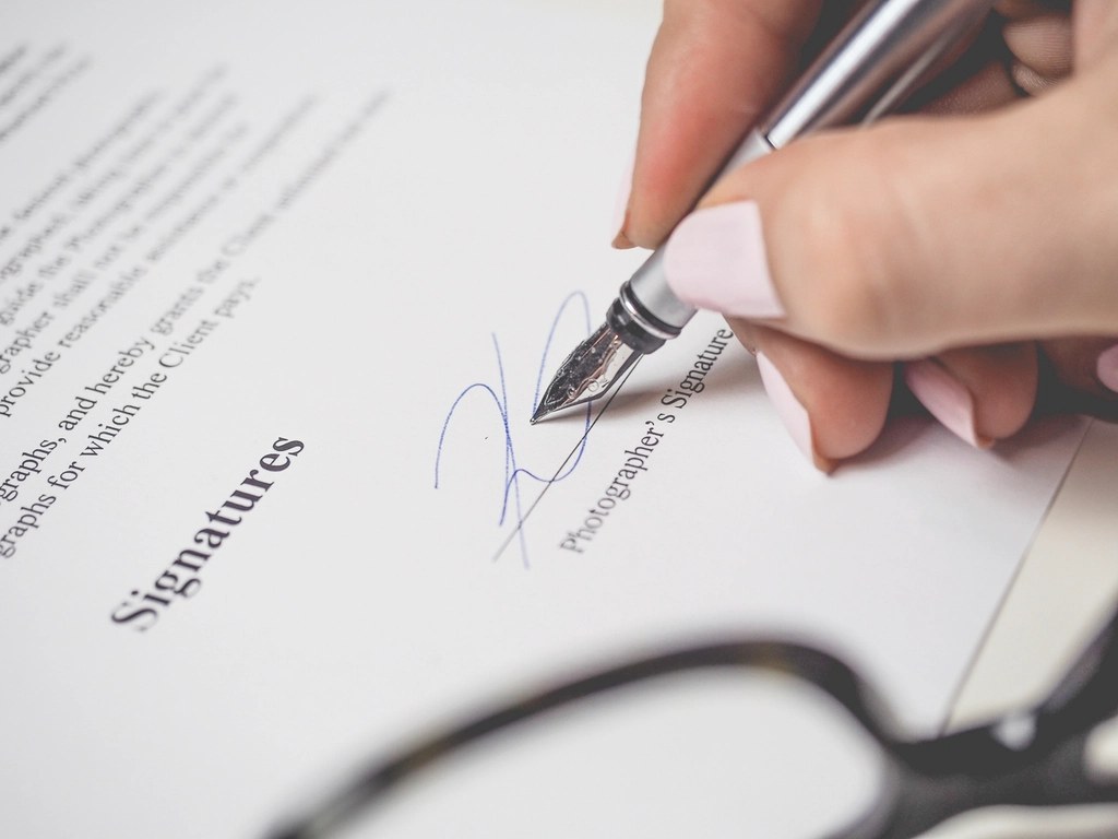 Hand signing a printed document with a silver pen