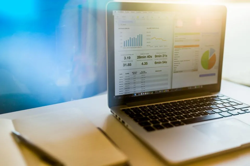 Laptop on a bright desk displaying colorful charts and slides